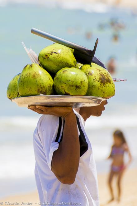 Imagem de um vendedor com uma bandeja com coco.